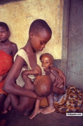 A young mother bosom feeds her five-month-old baby boy while holding her starving four-year-old daughter, near Anwa, Biafra, Aug. 5, 1968.The daughter died a few hours later