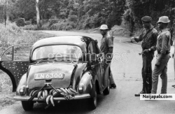 1968  Federal troops halt a car laden with food on the road to Onitsha, Nigeria, during the Biafran War. They are stopping all traffic on the road