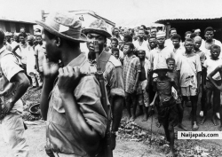 18 Jul 1968, Biafra --- Federal Troops Watched By Biafrans ---Villagers watch a group of Nigerian federal troops in a Biafran town. Biafra was a region of eastern Nigeria that seceded from 1967 to 1970