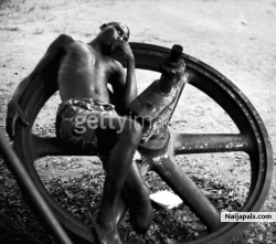 An amputee resting on a large wheel during the civil war in Biafra (now part of Nigeria), 1969