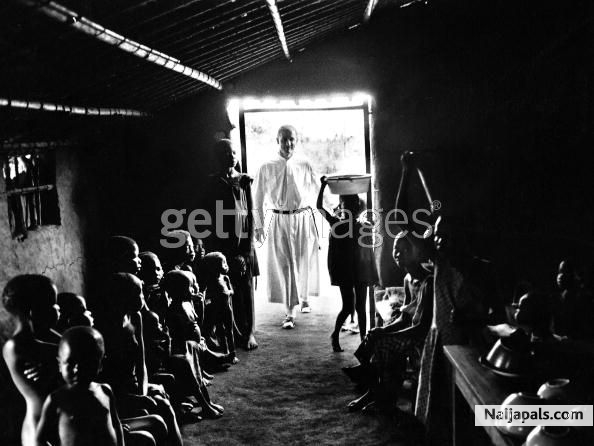 A figure in religious attire at the doorway of a building full of African children during the civil war in Biafra (now part of Nigeria), 1969. - click for next photo